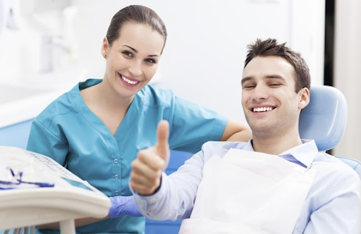 young man gives thumbs up at dentist